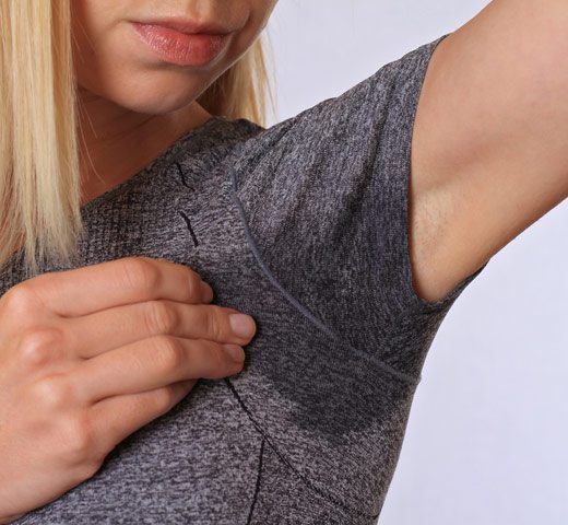 adult female with arm raised showing sweat stain on shirt