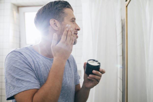 Handsome Young Man Applying Face Cream after a Morning Shave